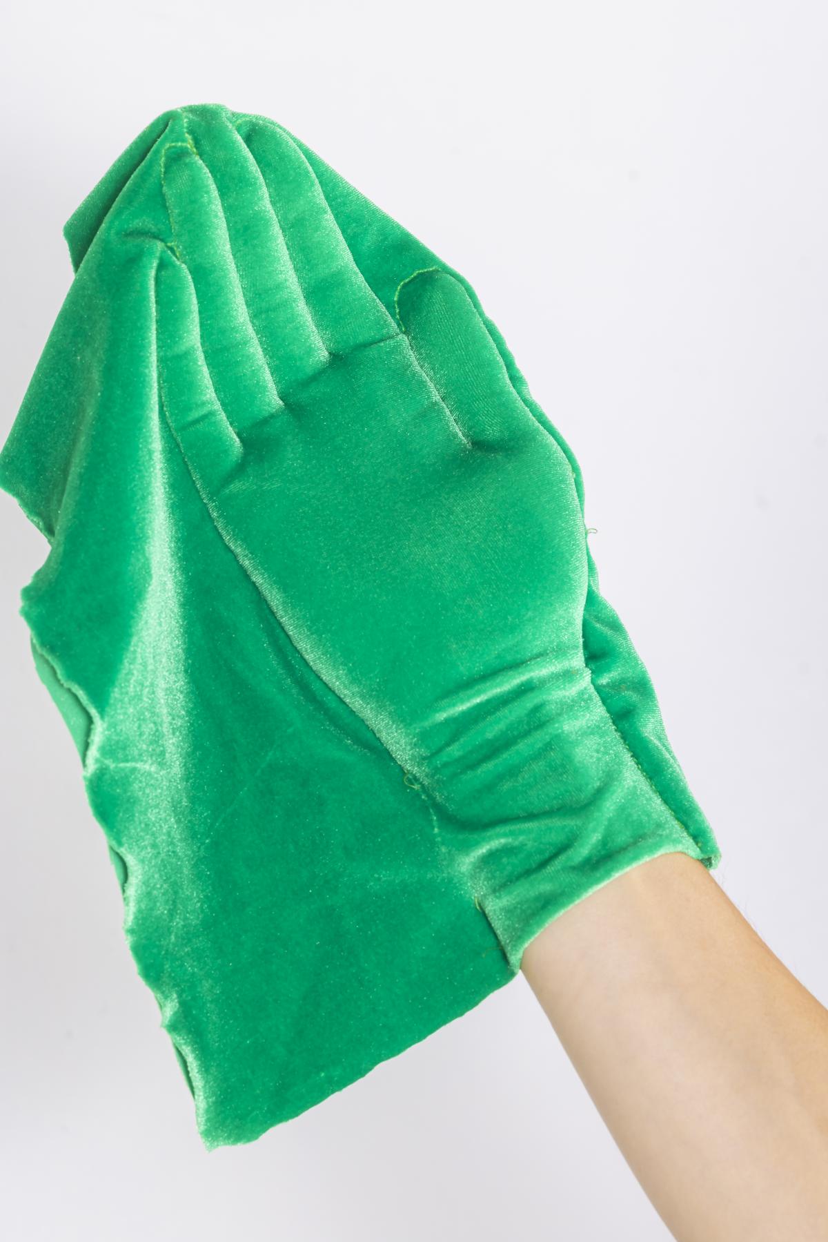 A raised hand and arm as seen from front, where the hand and part of the arm is covered by a beautiful green fabric which shows the outline of the skin.